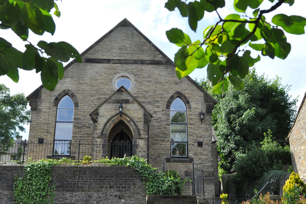 Stone church in Carleton, North Yorkshire, with arched windows and a wrought-iron fence.