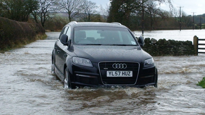 Flooded road in Carleton, North Yorkshire, with an Audi vehicle submerged in water.